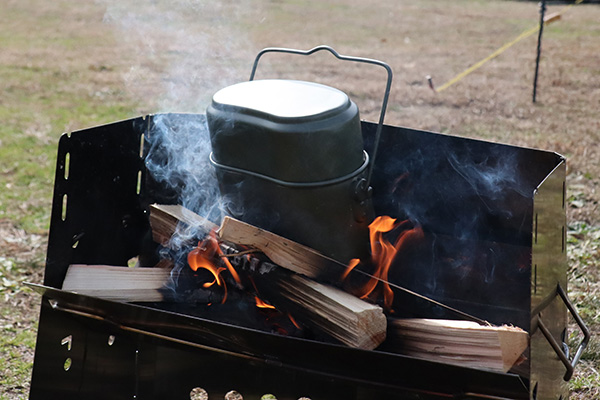 薪グリルの焚き火に飯盒を突っ込む